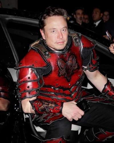 Elon Musk wearing a "Satan" suit bearing an upside down cross and a Baphomet goat head on that suit.